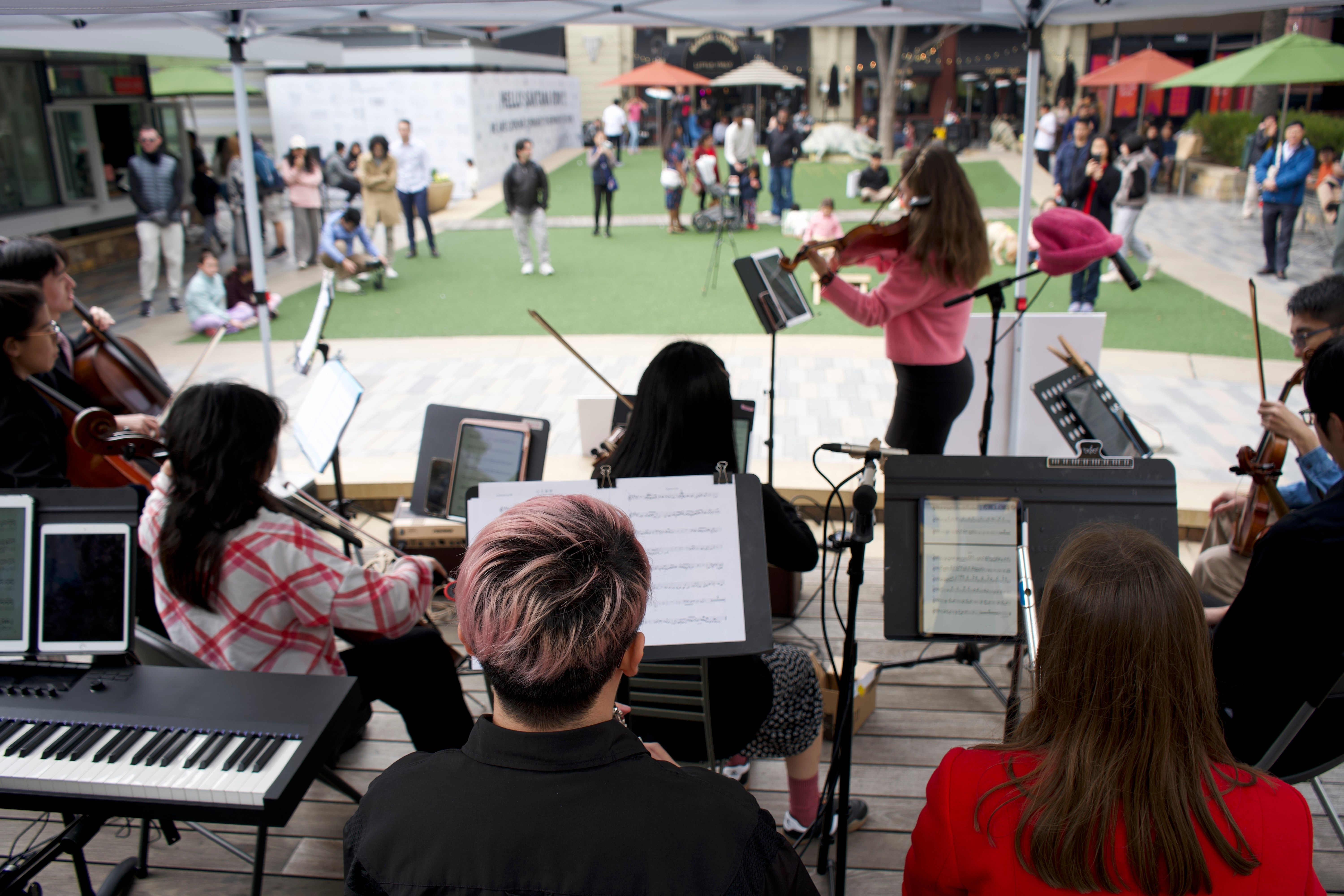 View from behind the stage showing musicians performing for outdoor audience at Santana Row